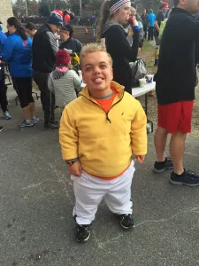 A smiling team member in a yellow jacket among runners before the race