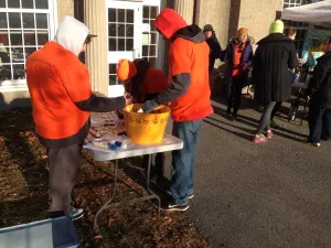 Volunteers in orange hoodies setting out treats at the table outside the race building