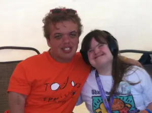 Two friends hugging and smiling, one in a Today's Special shirt and one wearing headphones