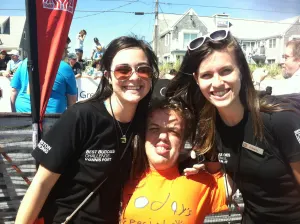 A team member in a Today's Special shirt between two smiling Best Buddies volunteers on a sunny day