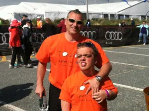 A team member and a supporter in matching orange Today's Special shirts beside the race course