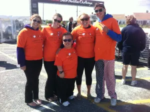 Five team members and supporters in Today's Special shirts posing under the Best Buddies Challenge arch
