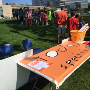 The Today's Special table with its hand-painted orange banner on the lawn as walkers gather