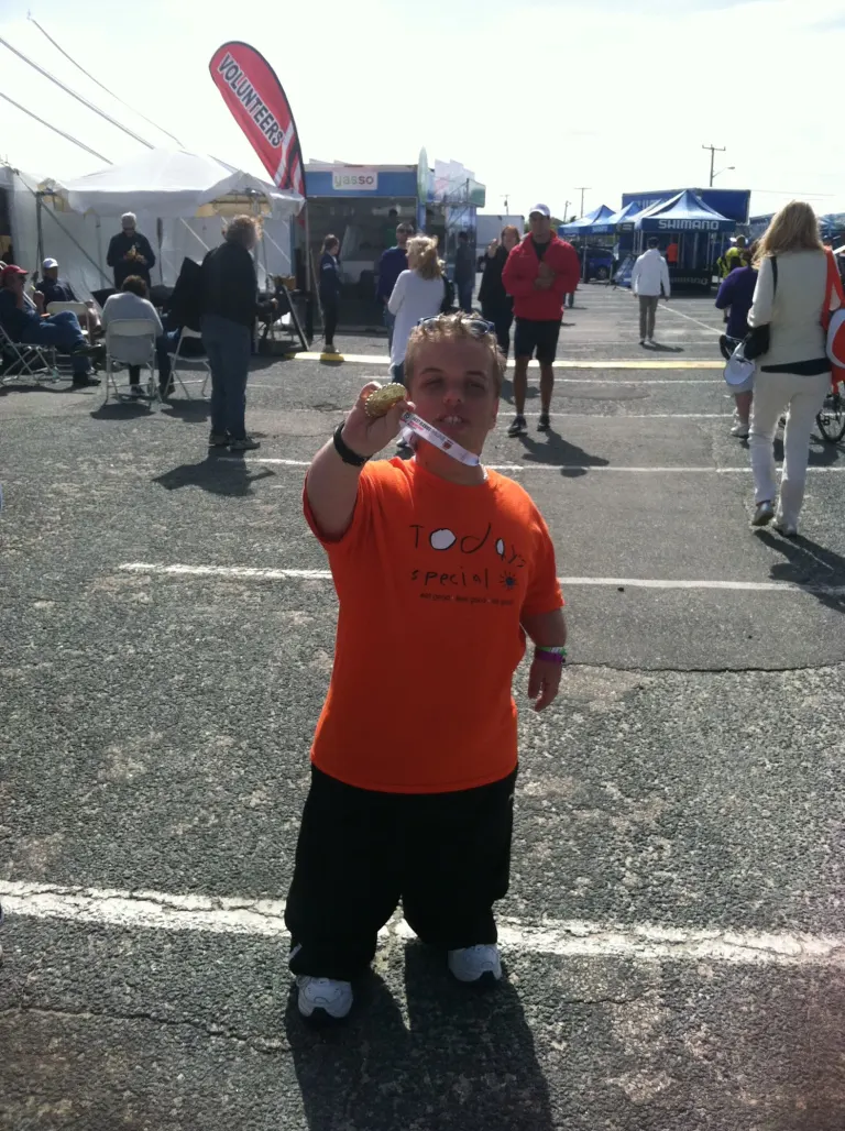 Harry outdoors at a community race, proudly showing his medal
