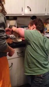 A young man in a green shirt cooking in a home kitchen