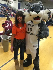 A team member in an orange Today's Special shirt with the University of New Hampshire wildcat mascot