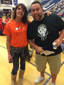 A team member in an orange shirt and a smiling supporter at the UNH Special Spirit game
