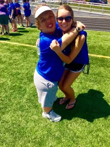 Two friends hugging on a sunny athletic field