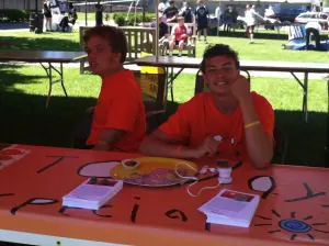 Two team members in orange shirts sitting at the Today's Special table on the lawn