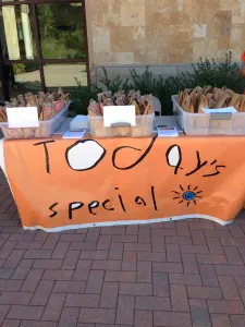 The Today's Special table with its orange banner and baskets of treats outside a building